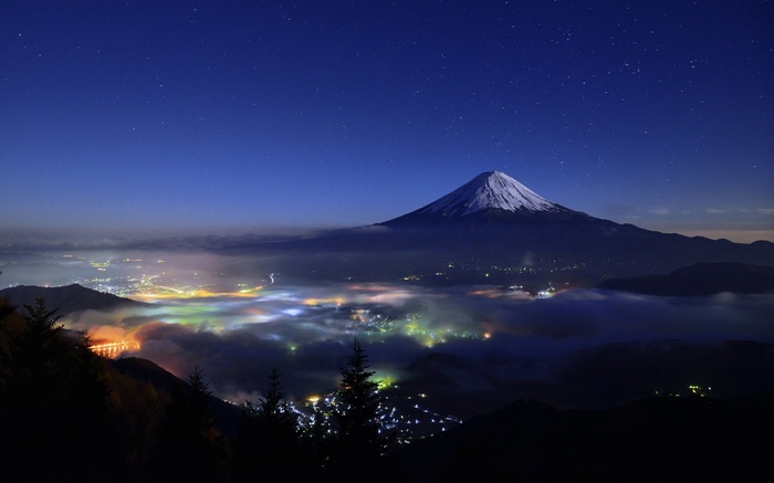 Mount Fuji at night with a starry sky and city lights