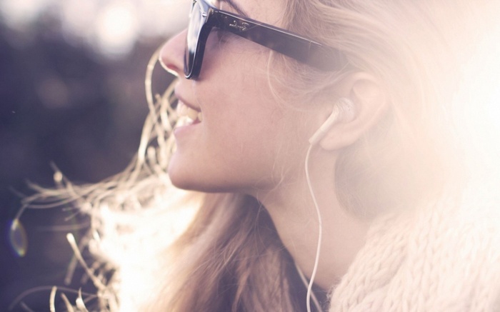 Woman wearing sunglasses and headphones listening to music