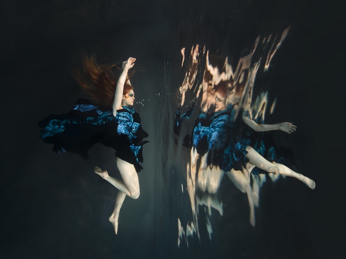 Woman in blue dress underwater with reflection