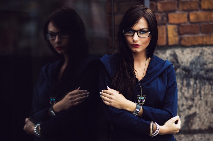 Woman with glasses and owl necklace reflected