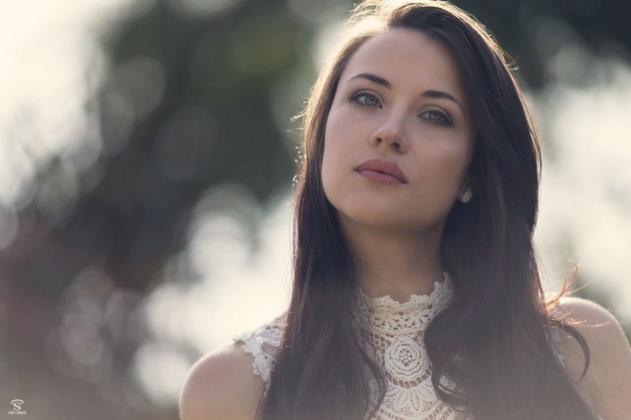Brunette woman with green eyes in a white lace top