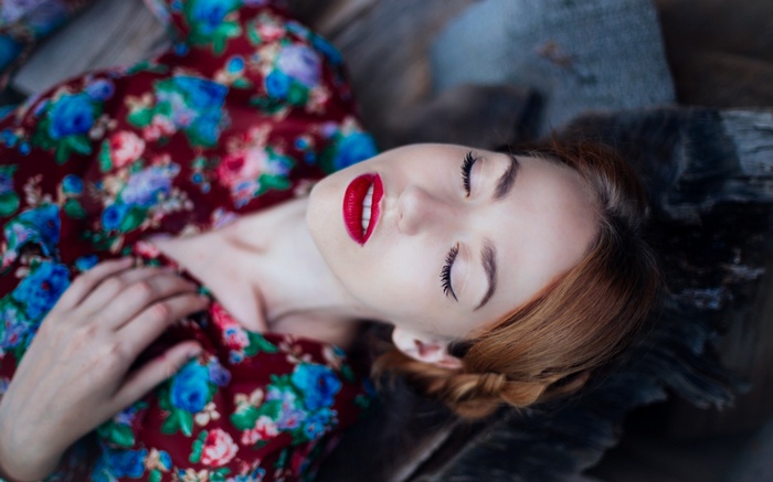 Woman with red lipstick lying down with closed eyes