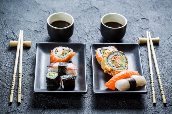 Two plates of sushi with soy sauce and chopsticks