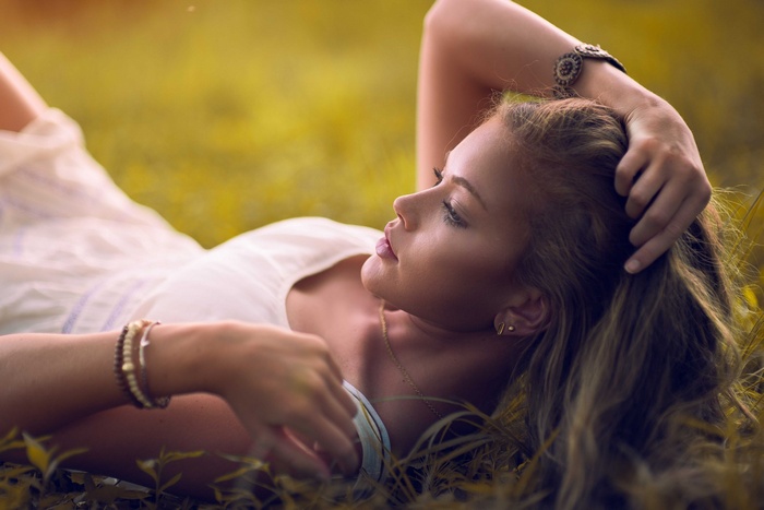 Woman lying in grass with hands in hair