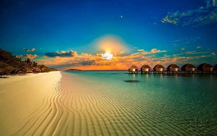Tropical beach resort with overwater bungalows at sunset