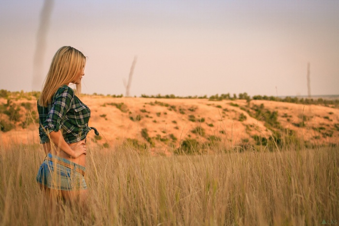 Woman in jean shorts and plaid shirt in field