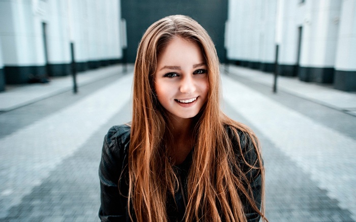 Young woman with long red hair smiling outdoors