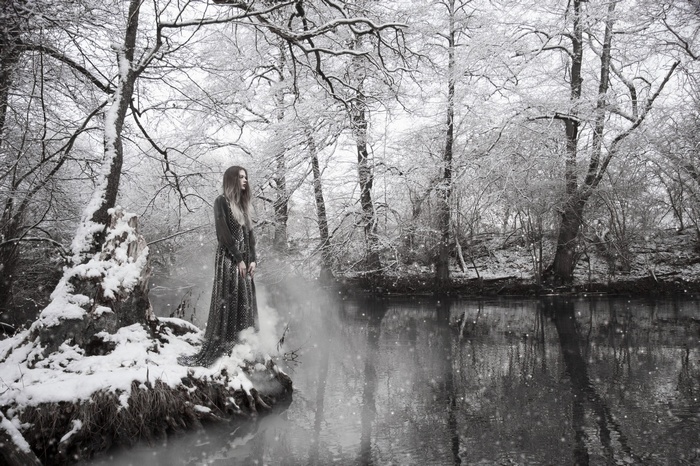Woman in a dress in a snowy forest by a river
