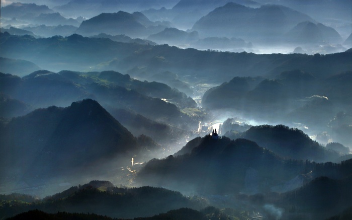Misty mountain valley with a village and church