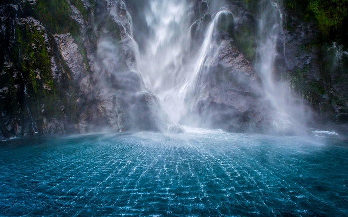 Milford Sound waterfall cascading into blue water