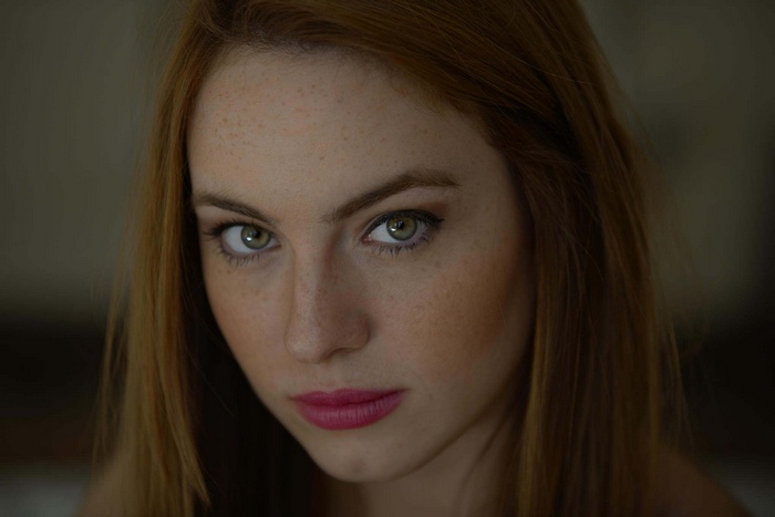 Portrait of a young woman with green eyes and freckles