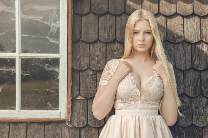 Blonde woman in lace dress by a window