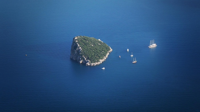 Island with sailboats in the blue sea