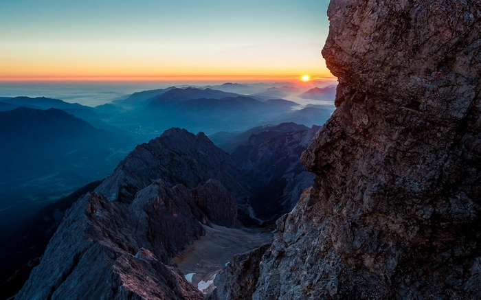 Sunrise over misty mountains from a rocky cliff