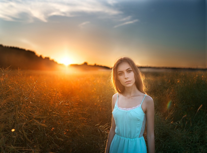 Woman in a blue dress in a field at sunset