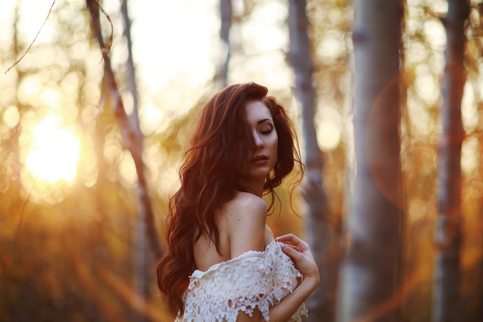 Redhead woman with closed eyes in a forest