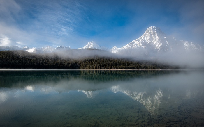 Snowy mountain peaks reflected in a misty lake in Canada