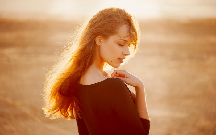 Woman with long red hair in sunlight