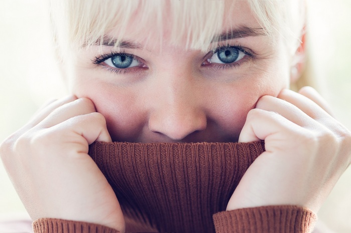 Woman with blonde bangs and blue eyes wearing a sweater