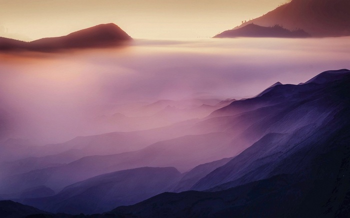 Misty mountains at sunrise with purple and orange hues