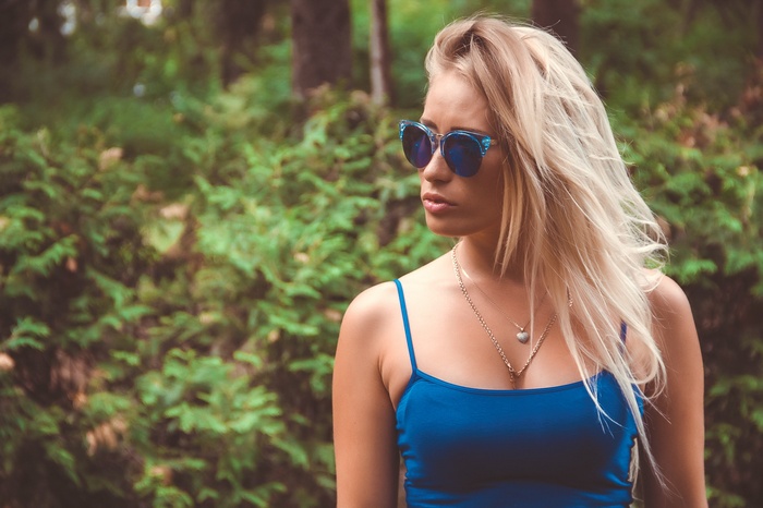Woman with blonde hair and sunglasses in a forest