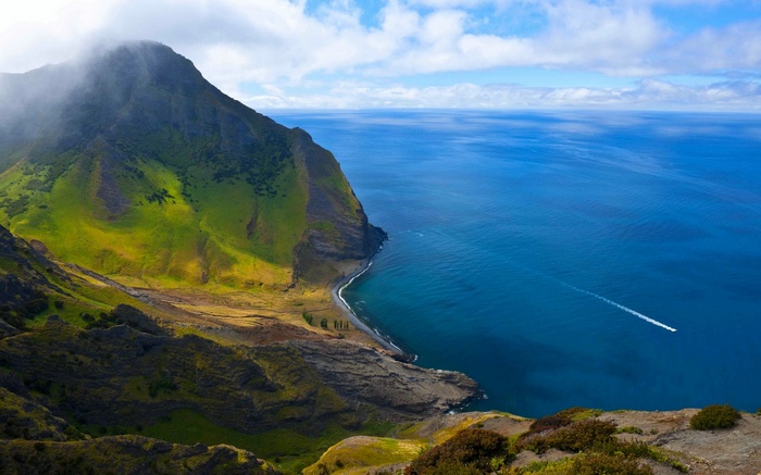 Green mountains and blue sea with a boat in Chile