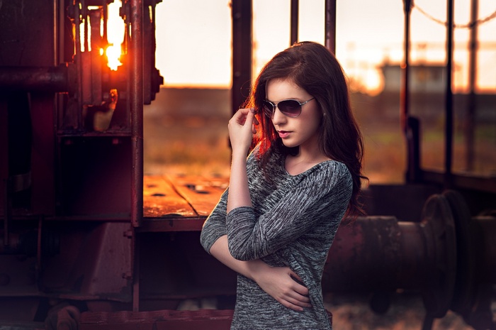 Woman with sunglasses at sunset near a train