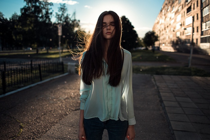 Woman with eyes closed in city street at sunset