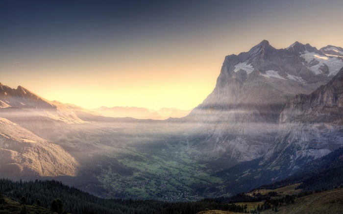 Misty valley with mountains at sunrise