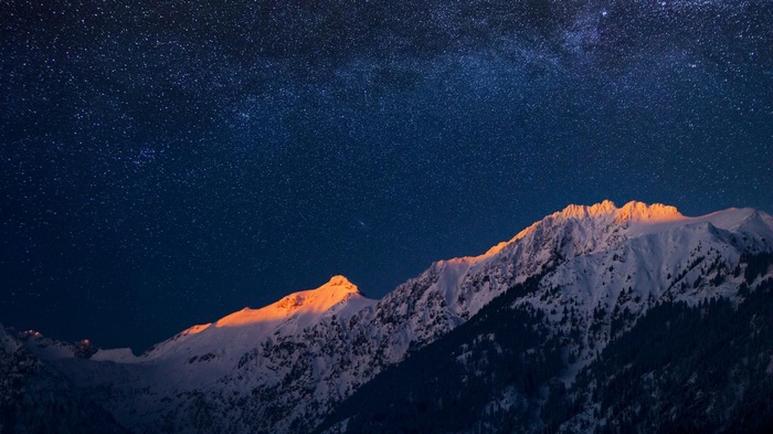 Snow-capped mountains under a starry night sky