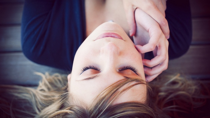 Woman with closed eyes lying on a wooden surface