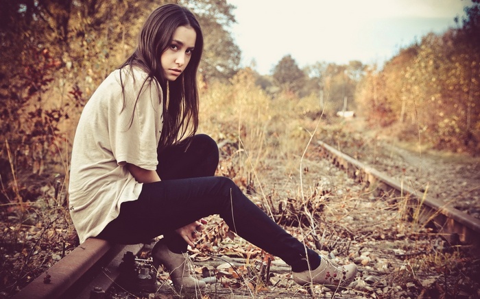 Young woman with long hair on railway tracks in fall