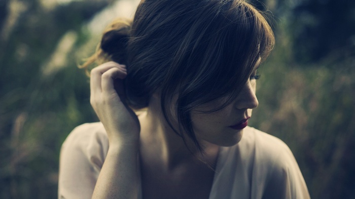 Woman with dark wavy hair touching her head