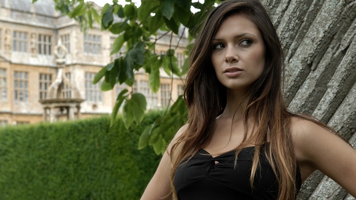 Louisa Marie posing by a tree with a building behind