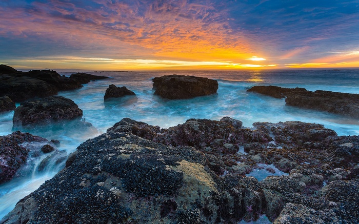 Sunset over the rocky coast with waves crashing