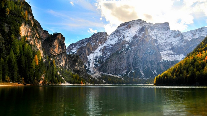 Lake and mountains with snowy peaks and autumn forest