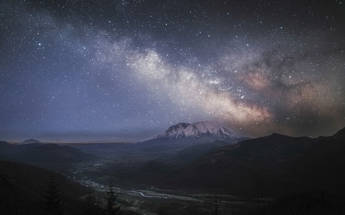 Milky Way over a snowy mountain peak and valley