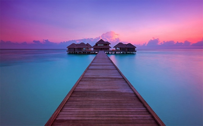 Overwater bungalows on a wooden pier at sunset