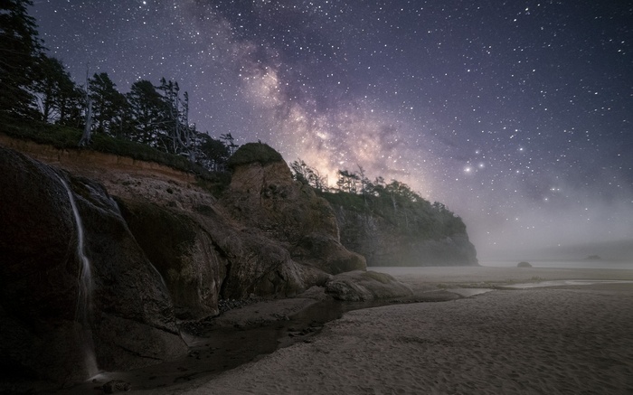 Milky Way over a misty coast with a waterfall