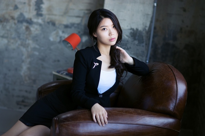 Asian woman in a black suit sitting in a chair