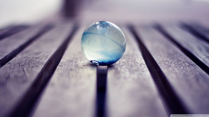 Translucent blue marble on a wooden surface