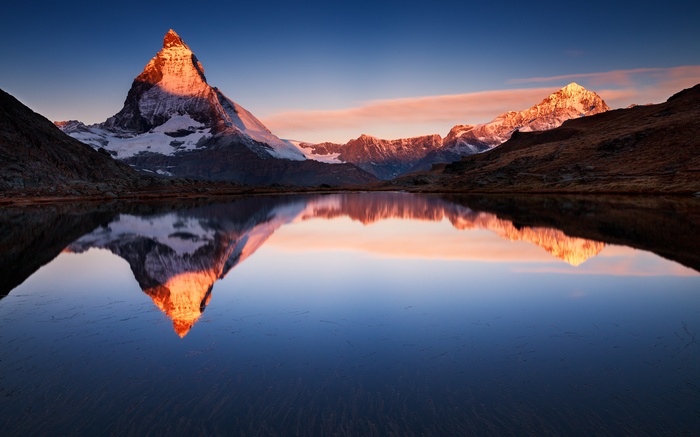 Matterhorn mountain reflected in a calm lake at sunrise