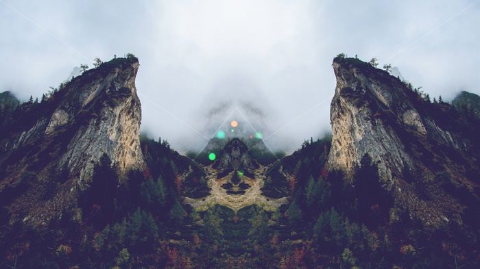 Mirrored mountains and forest with geometric overlay
