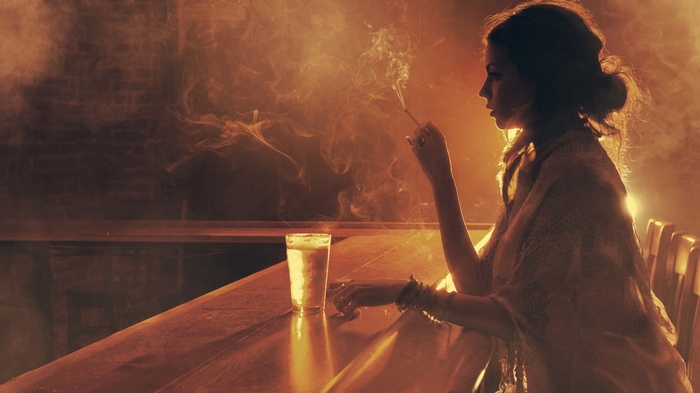 Woman smoking at a bar with a drink