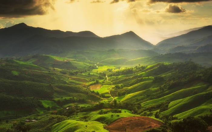 Sunlight over green rolling hills and mountains
