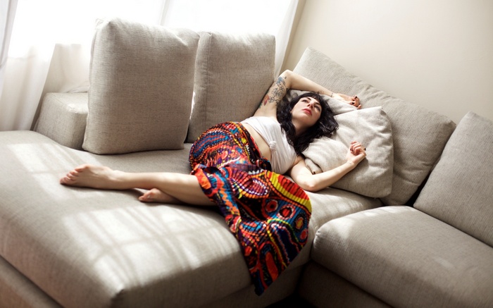 Woman with tattoo lying on a couch