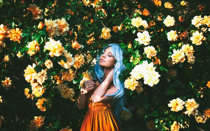 Woman with blue dyed hair among yellow roses