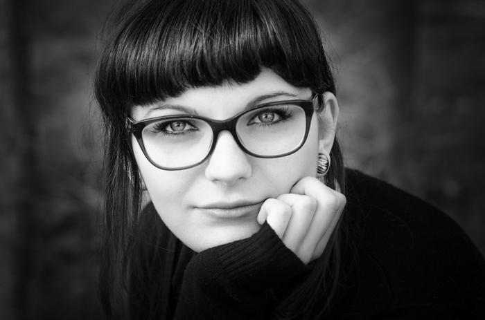 Woman with glasses resting her chin on her hand