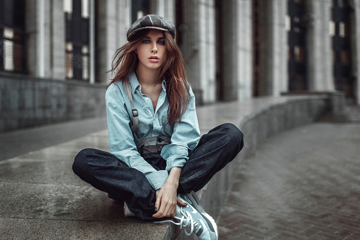 Woman wearing a cap and suspenders sitting outdoors
