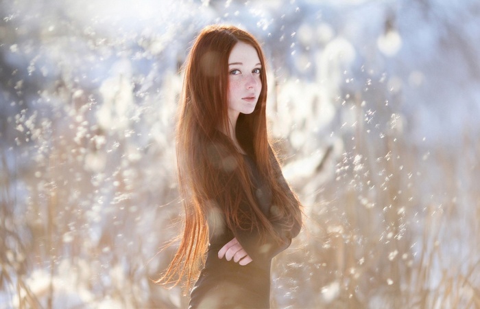 Redhead woman with freckles in a snowy field